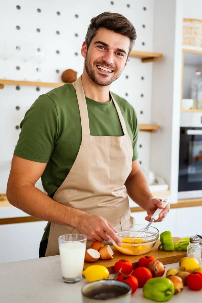 Michael Carter, founder of SwicyBee, whisking eggs in his NYC kitchen surrounded by fresh vegetables and ingredients.