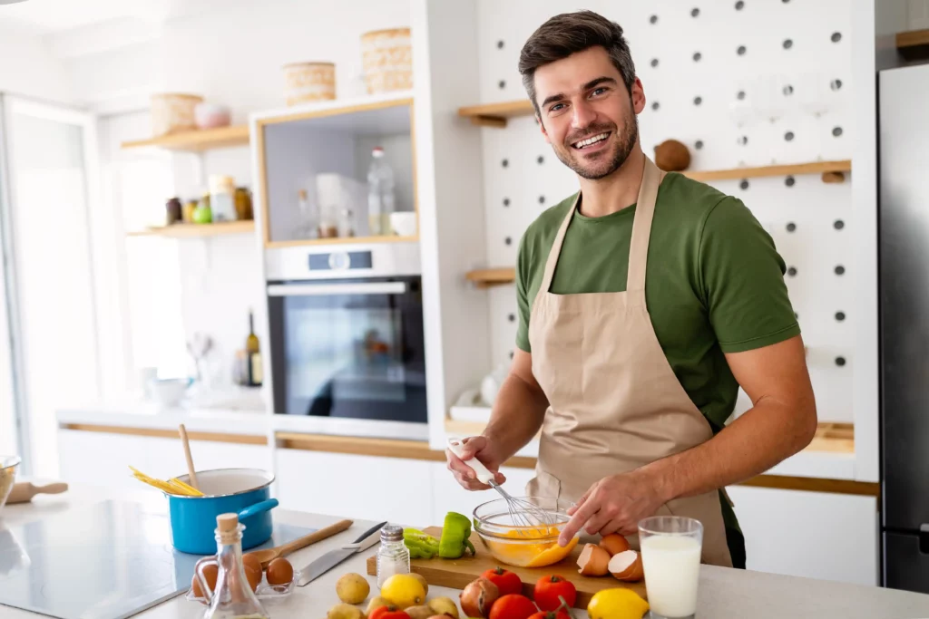 Michael Carter, founder of SwicyBee, whisking eggs in his NYC kitchen surrounded by fresh vegetables and ingredients.